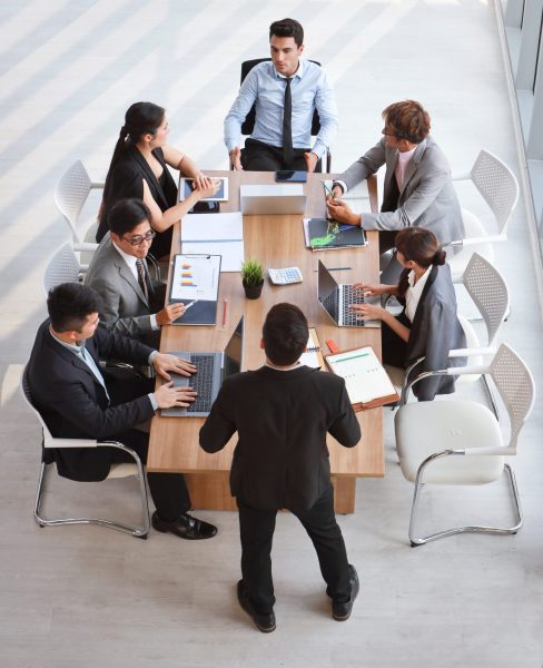 caucasian lecturer giving public presentation with company business graph result on white board in meeting room and multiethnic business people are paying attention (training or seminar concept) top view image of caucasian lecturer giving public presentation with company business graph result on white board in meeting room and multiethnic business people are paying attention (training or seminar concept)